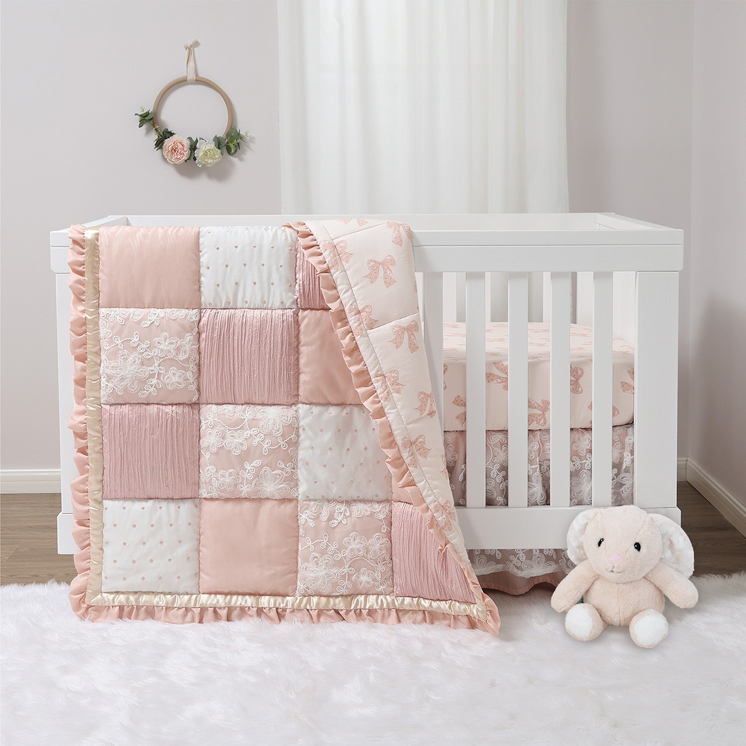 Crib with a pink and white checkered quilt and teddy bear in a nursery setting.